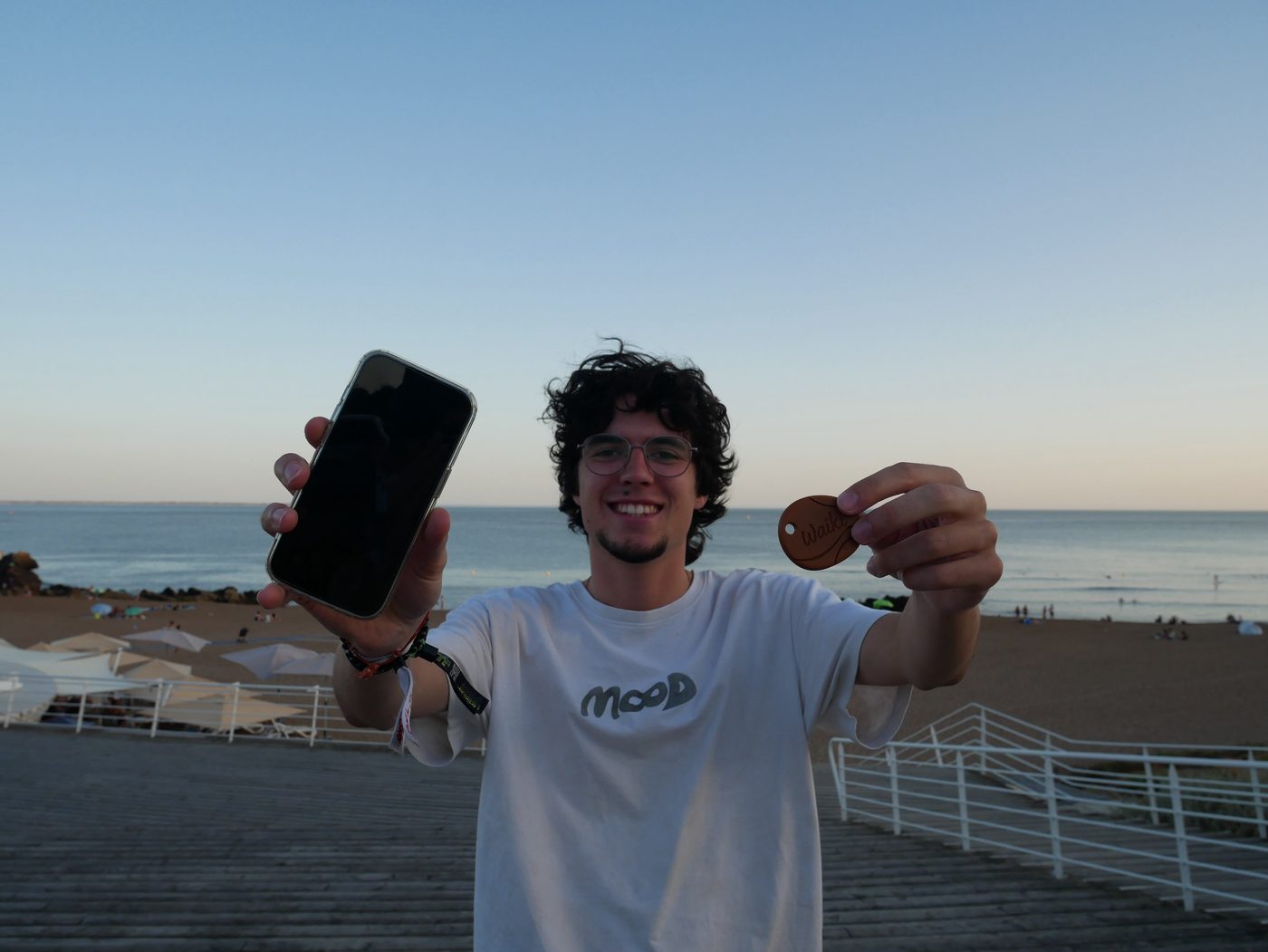 Célestin, le téléphone dans une main et la clé Waiki dans l'autre, devant la mer à Saint-Marc